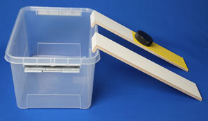 Puck liegt auf einer von zwei Rampen mit unterschiedlicher Beschichtung vor einer Plastikbox.