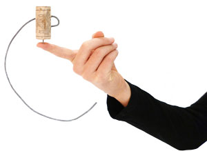 Hand balanciert Korken mit Draht auf Finger – Beispiel für asymmetrisches Gleichgewicht.